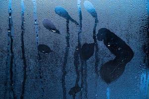 huella de mano en vidrio empañado, símbolo de sensualidad en superficie mojada. foto