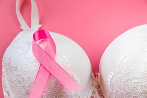 Breast Cancer Awareness Month. Women's bra and pink ribbon on bright background. Health care concept, oncology diagnostics. photo