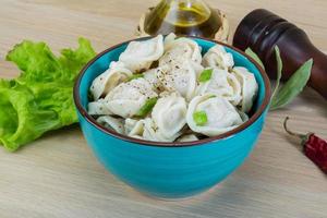 Boiled russian dumplings in a bowl on wooden background photo