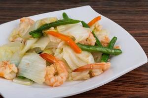 ensalada de gambas en el plato y fondo de madera foto