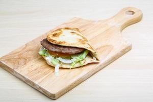 Greek pita on wooden board and wooden background photo