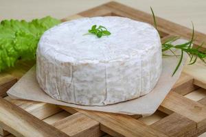 queso camembert sobre tabla de madera y fondo de madera foto