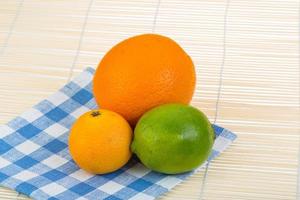 Orange, lime, tangerine on wooden background photo