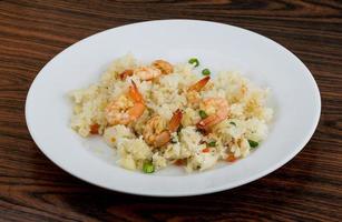 Fried rice with prawns on the plate and wooden background photo