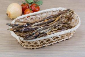 Dry fish in a basket on wooden background photo
