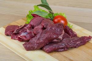 Raw venison on wooden board and wooden background photo