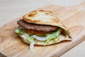 Greek pita on wooden board and wooden background photo