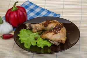 Roasted chicken leg on the plate and wooden background photo