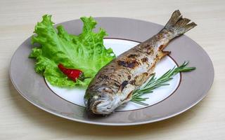 Grilled trout on the plate and wooden background photo