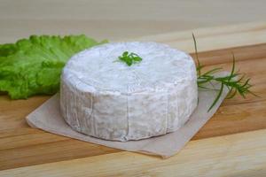 Brie cheese on wooden board and wooden background photo