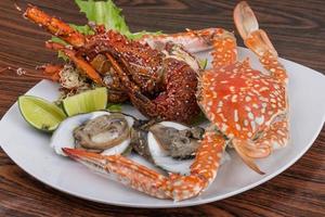 Spiny lobster, crab and oyster on the plate and wooden background photo