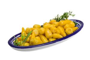 Yellow marinated pepper in a bowl on white background photo