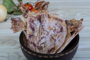 Dried squid in a bowl on wooden background photo