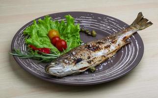 Grilled trout on the plate and wooden background photo