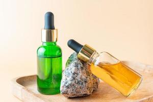 Aesthetic minimalist beauty care therapy concept. Organic serum oil cosmetics bottles on stone against beige background. Body, skin, face treatment product composition photo