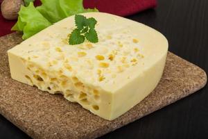 Yellow cheese on wooden board and wooden background photo