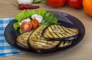 Grilled aubergine on the plate and wooden background photo