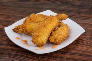 tempura de gambas fritas en el plato y fondo de madera foto