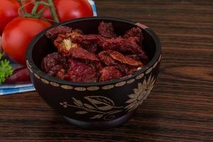 Dried tomtoes in a bowl on wooden background photo