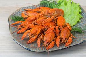 Boiled crayfish on the plate and wooden background photo