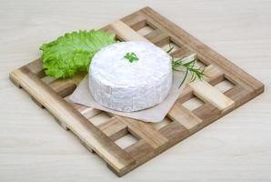 queso camembert sobre tabla de madera y fondo de madera foto