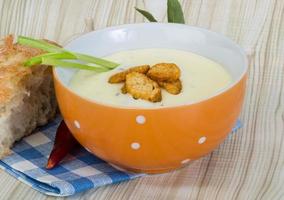 Cheese soup with croutons in a bowl on wooden background photo