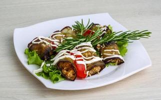 Aubergine roll on the plate and wooden background photo