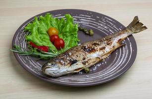 Grilled trout on the plate and wooden background photo