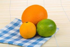 Orange, lime, tangerine on wooden background photo