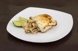 Grilled cuttlefish on the plate and wooden background photo