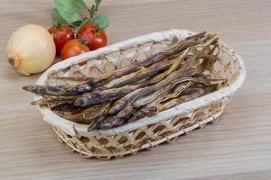 Dry fish in a basket on wooden background photo