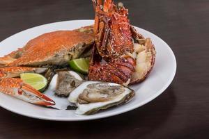 Spiny lobster, crab and oyster on the plate and wooden background photo