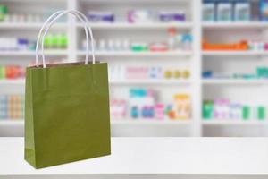 Paper bag on Pharmacy drugstore counter table with medicine and healthcare product on shelves blur background photo