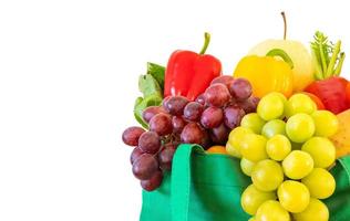 Fresh fruits and vegetables grocery product in green reusable shopping bag isolated on white background with clipping path photo