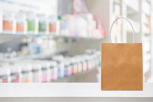 Paper bag on Pharmacy drugstore counter table with medicine and healthcare product on shelves blur background photo