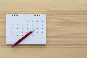 página de calendario con bolígrafo sobre fondo de mesa de madera foto