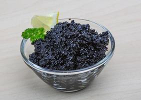 Black caviar in a bowl on wooden background photo