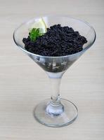 Black caviar in a bowl on wooden background photo