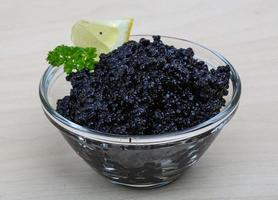 Black caviar in a bowl on wooden background photo
