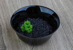 Black caviar in a bowl on wooden background photo