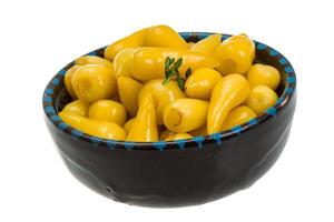 Yellow marinated pepper in a bowl on white background photo