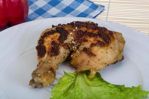 Roasted chicken leg on the plate and wooden background photo