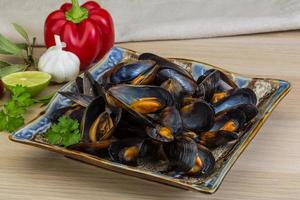 Mussels on the plate and wooden background photo