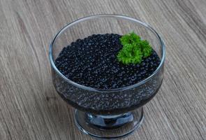 Black caviar in a bowl on wooden background photo