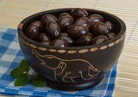 Almond in chocolate in a bowl on wooden background photo