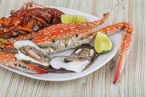 Spiny lobster, crab and oyster on the plate and wooden background photo