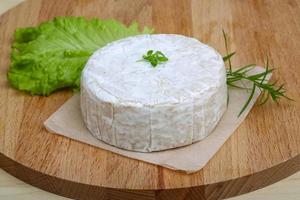 Brie cheese on wooden board and wooden background photo