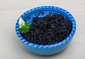 caviar negro en un recipiente sobre fondo de madera foto