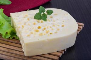 Yellow cheese on wooden board and wooden background photo