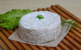 Camembert cheese on wooden board and wooden background photo